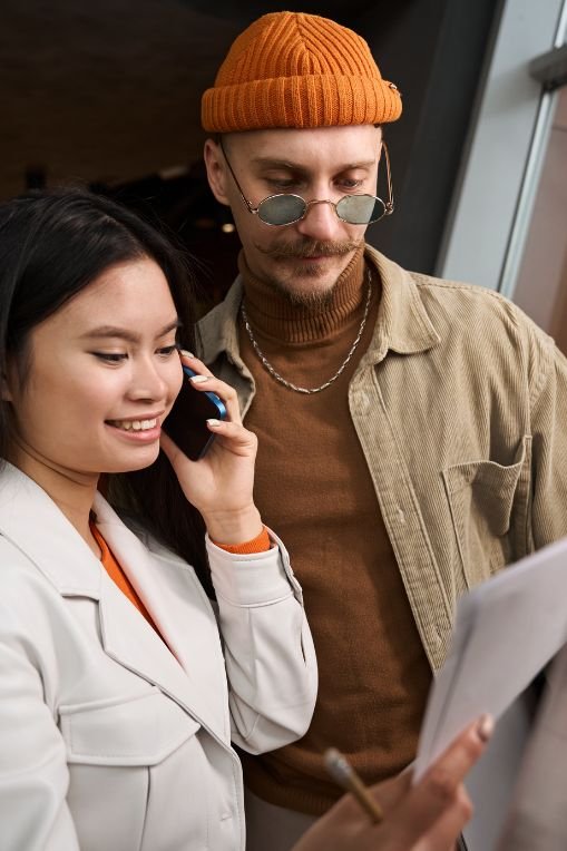 Marketing trends. Young professionals reviewing a document together, with one person on a phone call — teamwork in a modern business setting.